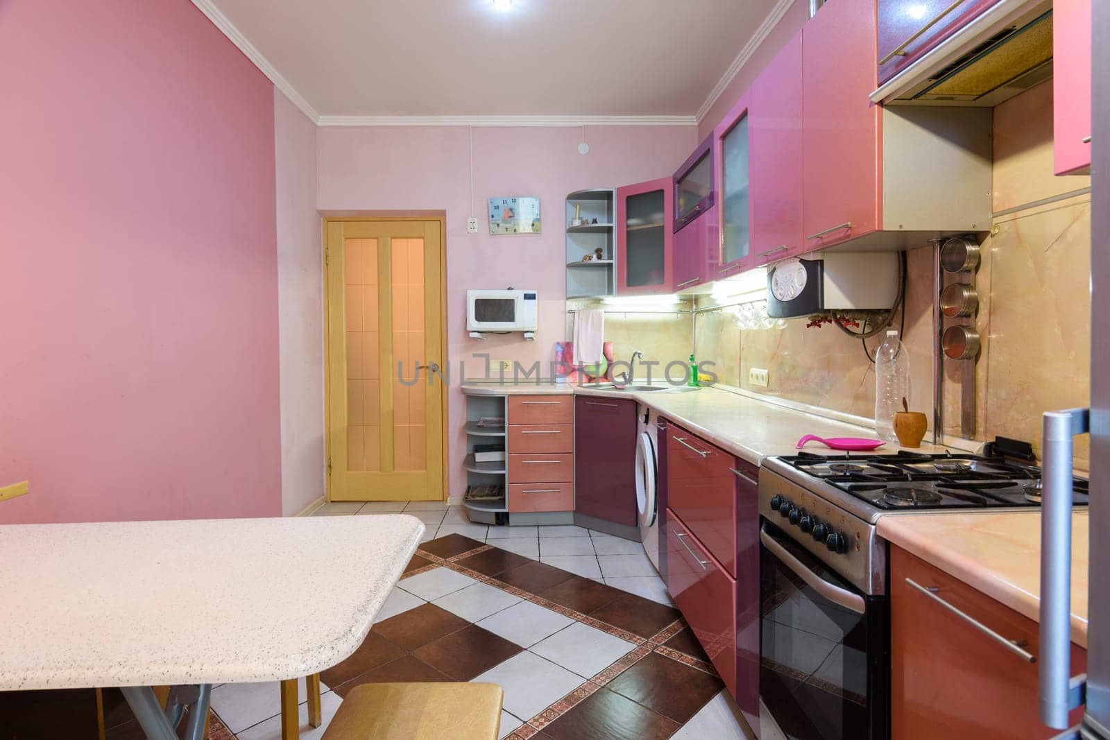 Fragment of the interior of a small furnished kitchen, view from the window to the front door