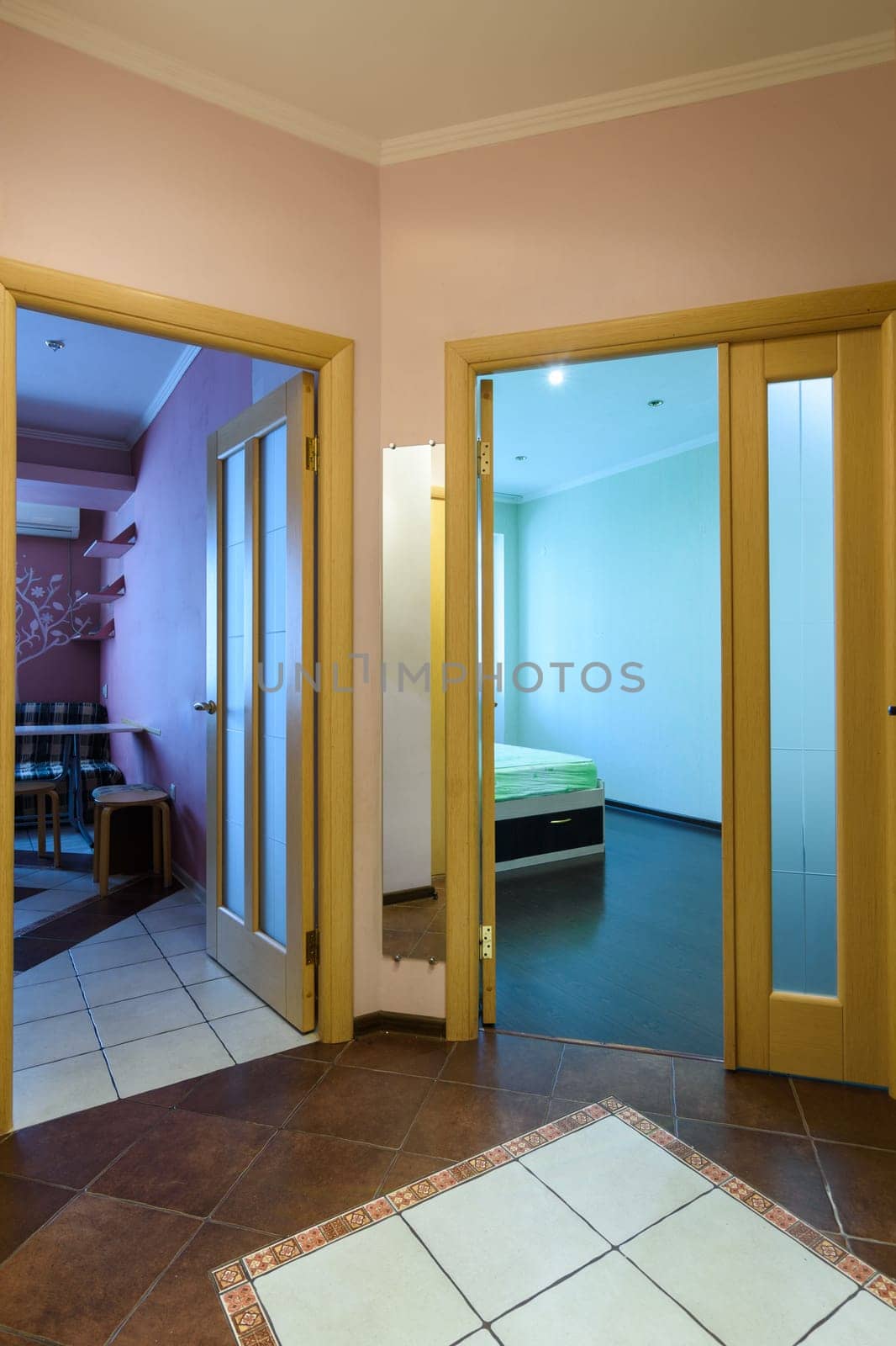 View from the hallway to the open doors to the kitchen and a room in a studio apartment
