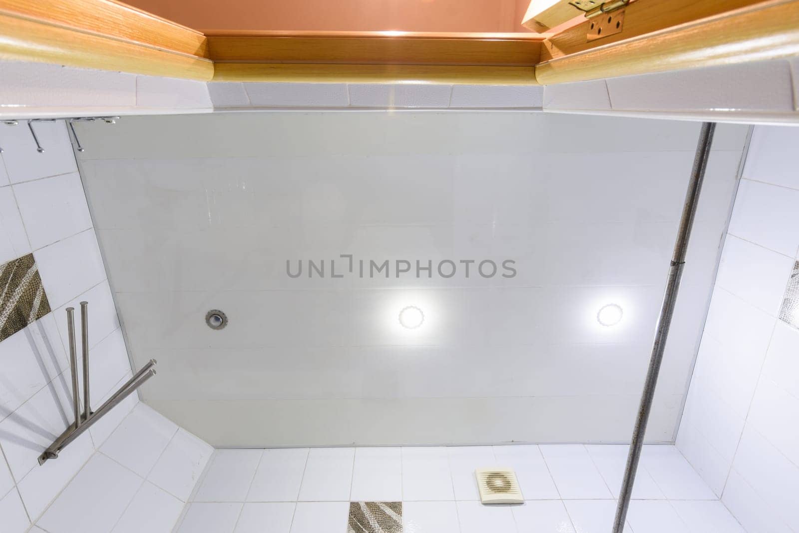 A fragment of a bathroom interior, a view of the ceiling made of plastic panels with three lamps, one light bulb burned out