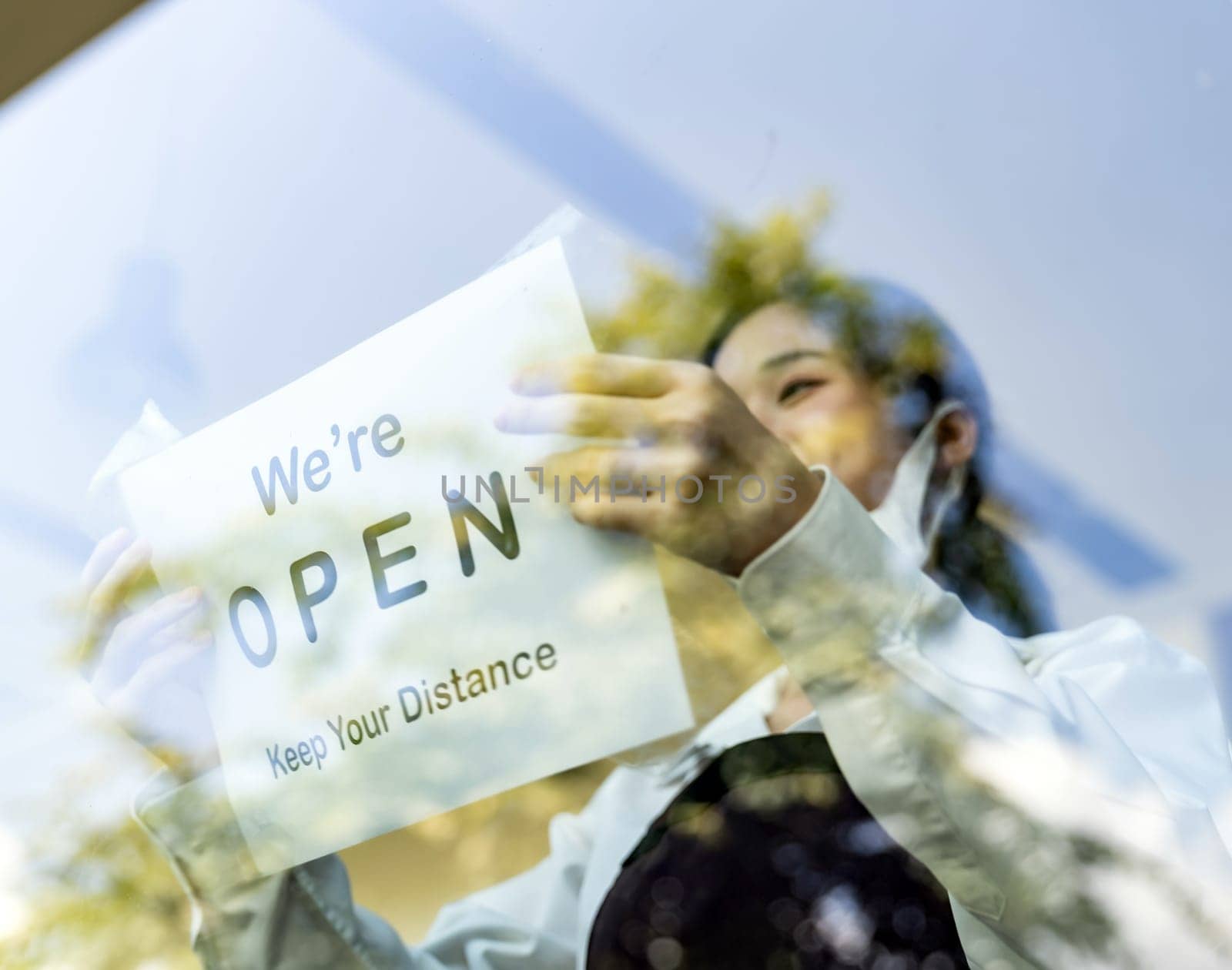 Focus on restaurant signage. Asian female waitress putting on open signage with social distance for new normal restaurant. New normal restaurant lifestyle concept.