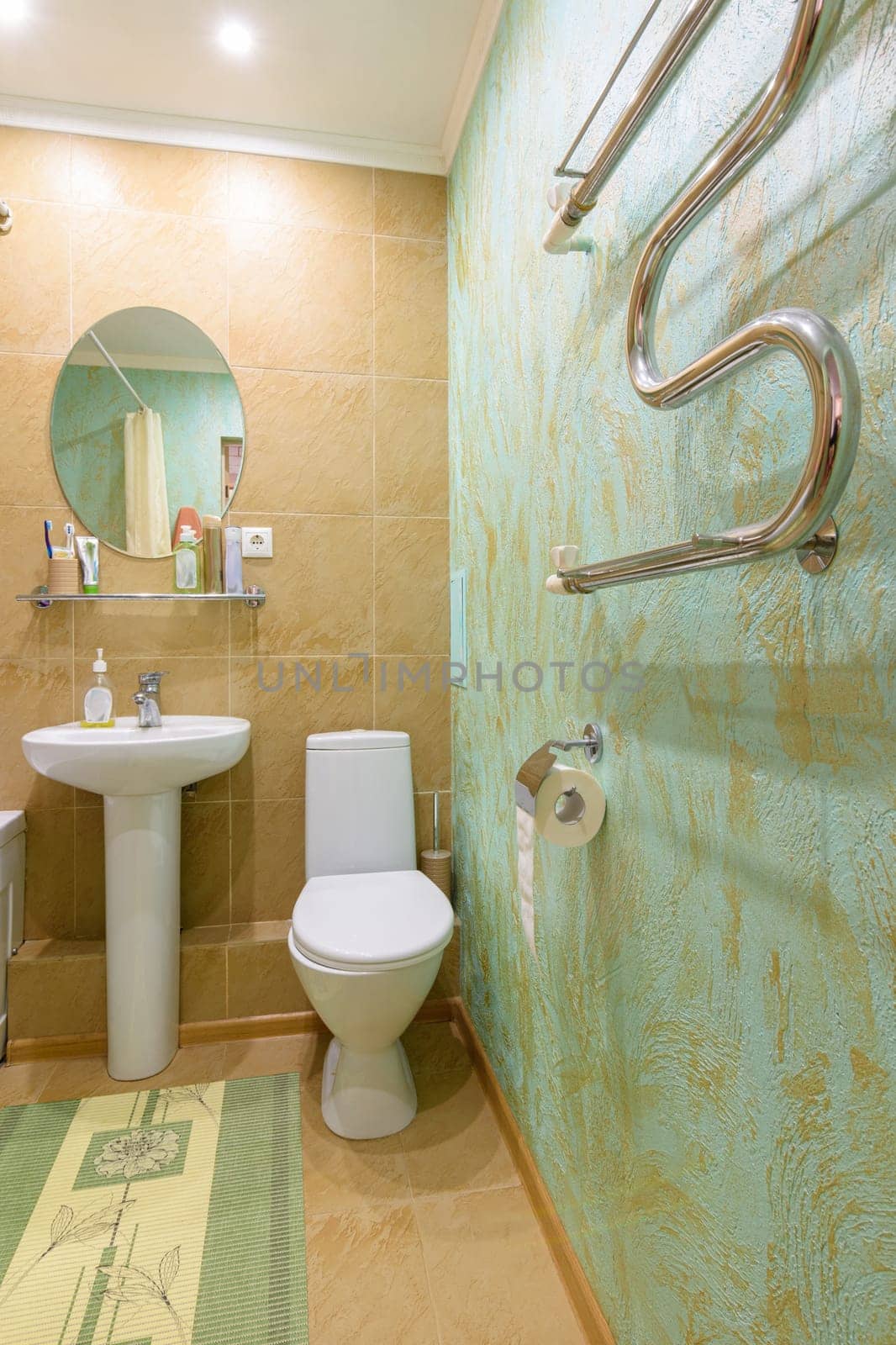 Fragment of the bathroom interior, view of the toilet and washbasin, a heated towel rail is installed on the wall