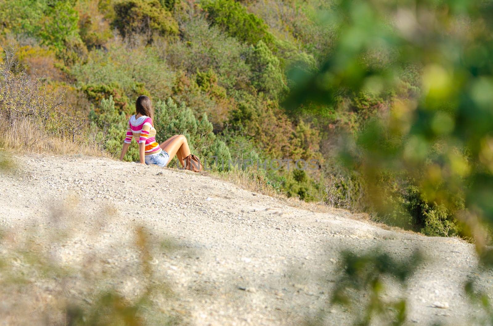 A girl sits on a hill and enjoys a wonderful view