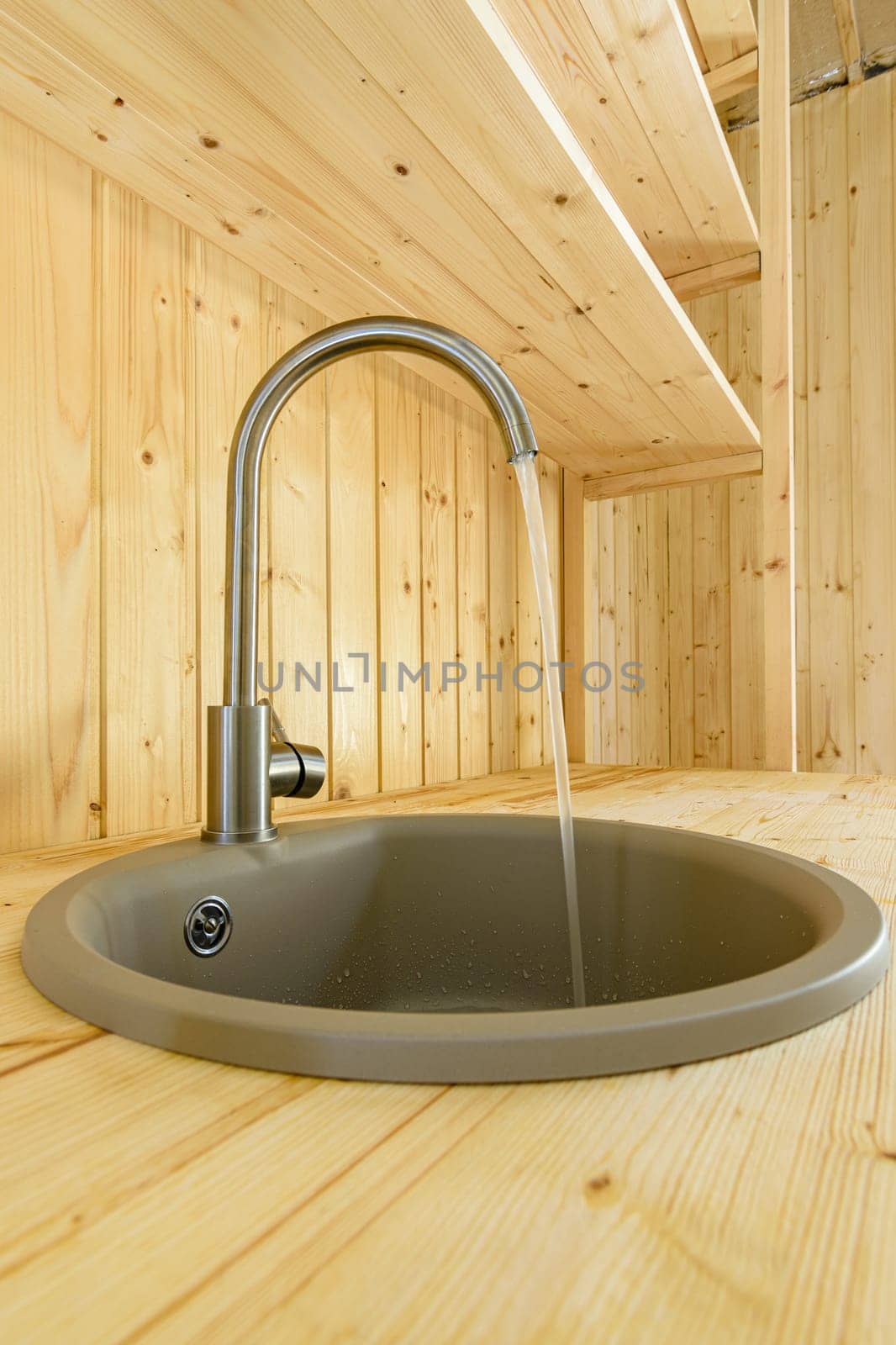 In a kitchen made of natural wood, water flows from the mixer