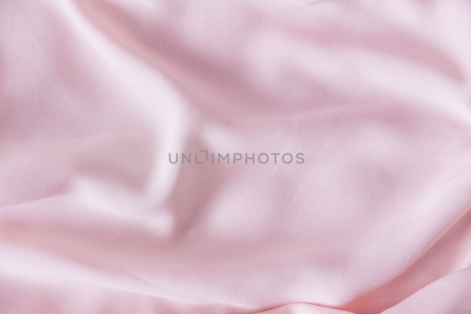 Pink wrinkled silk fabric. The pink fabric is laid out waves. Pink fabric background or texture