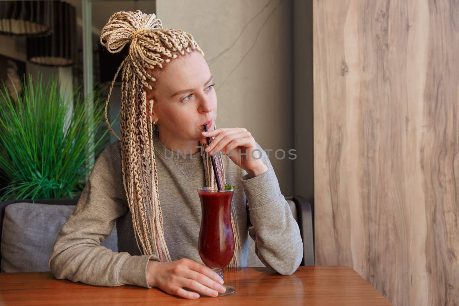 Young hipster woman kanekalons drinking berry cocktail smoothie with a straw.