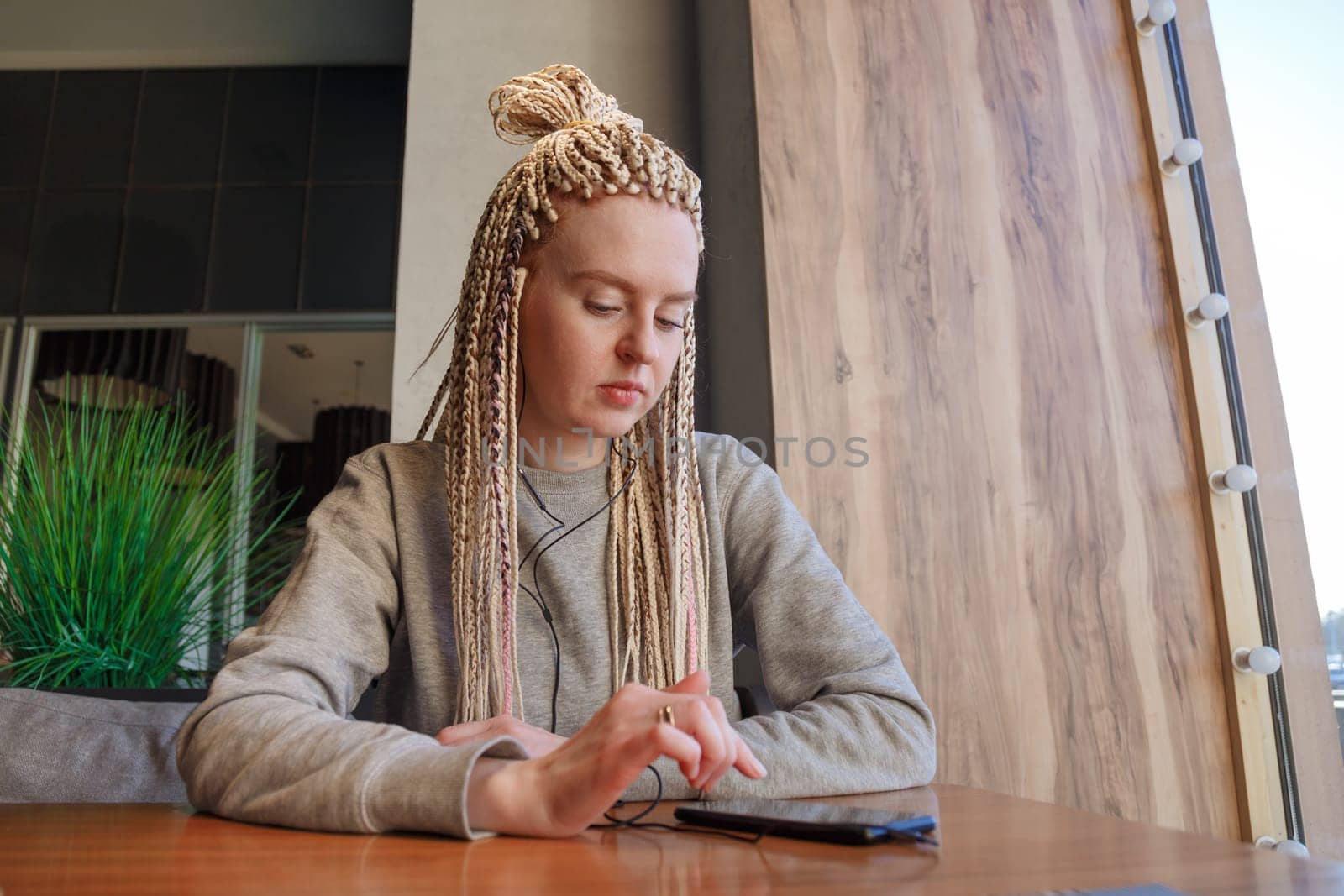 Worried young hipster woman in cafe. Lateness or punctuality concept
