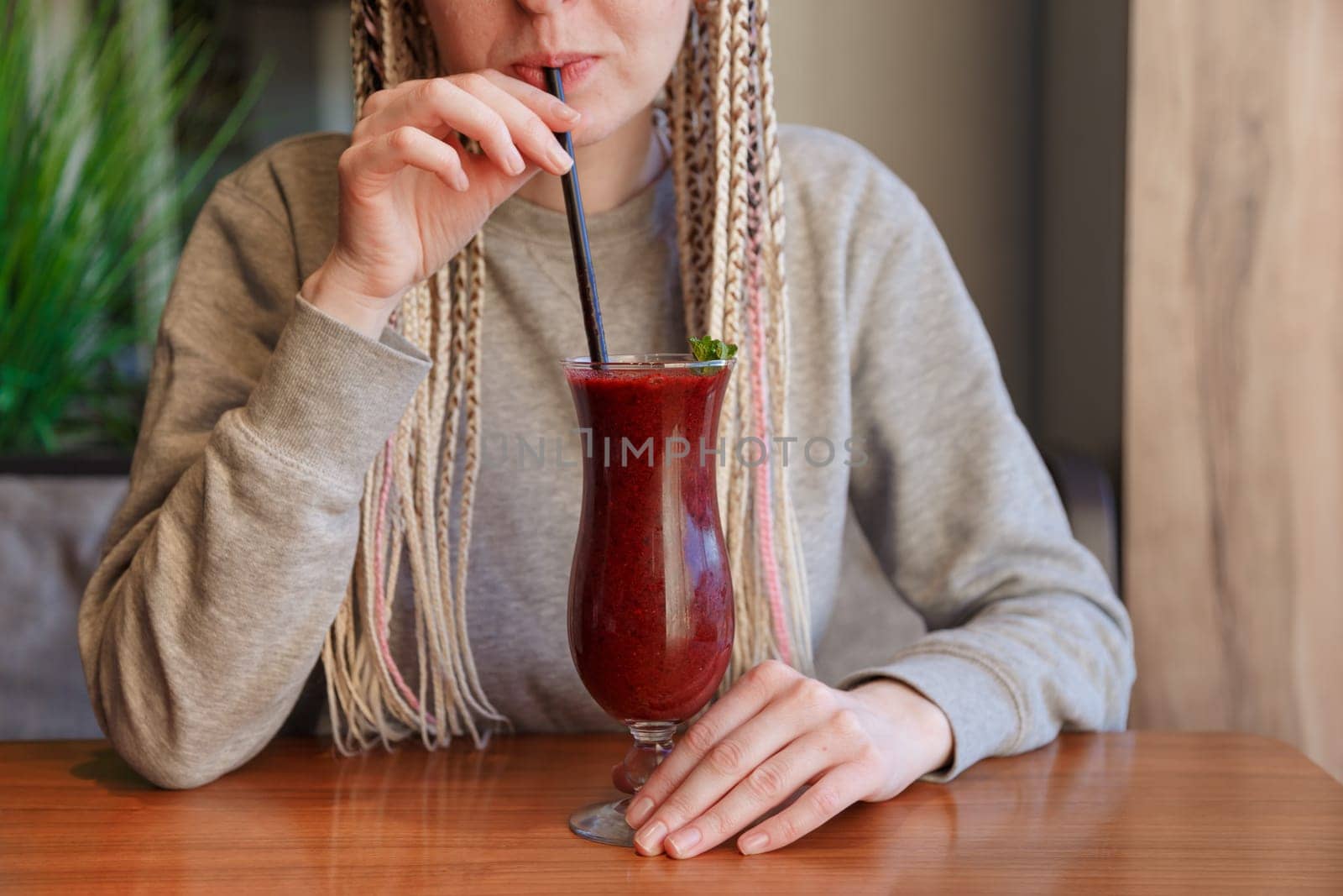 Young hipster woman kanekalons drinking berry cocktail smoothie with a straw.