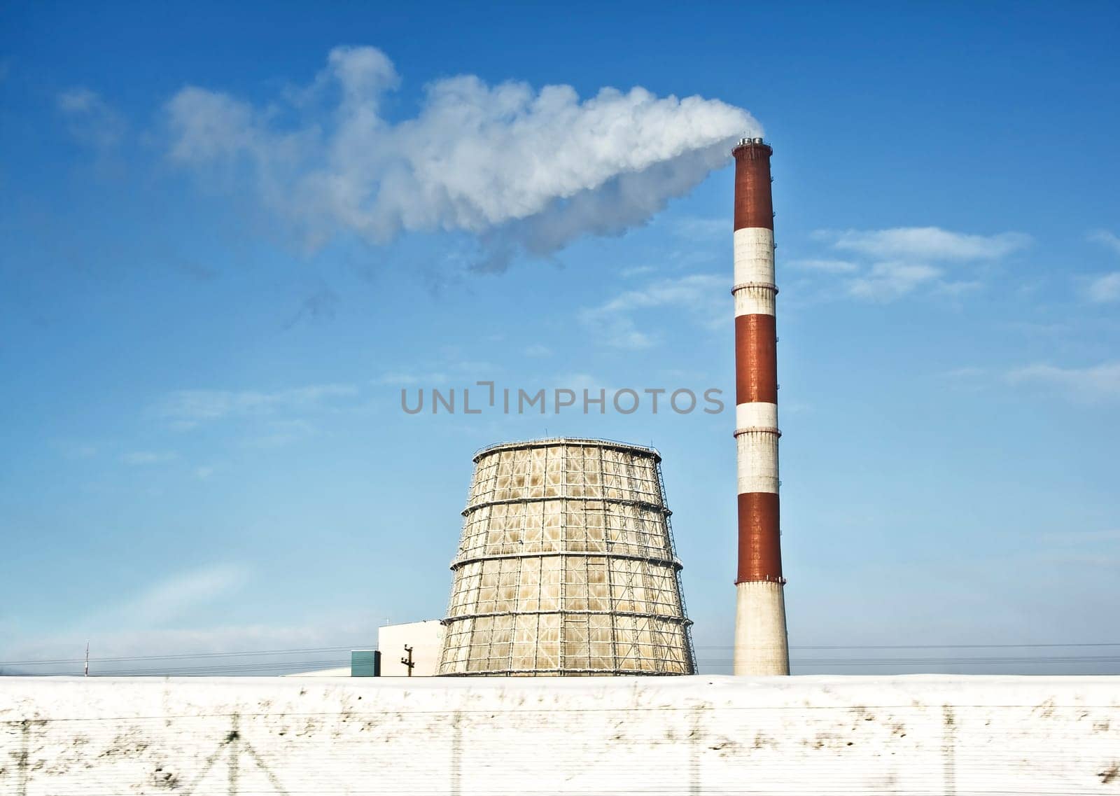 Power plant in winter sunny day with smoke coming out of pipe