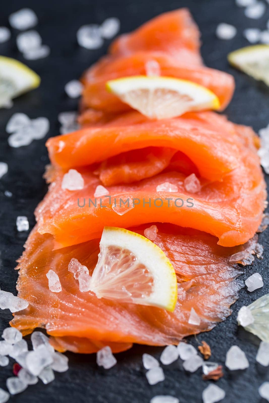 Smoked salmon with lemon and sea salt on black background. Healthy food concept.