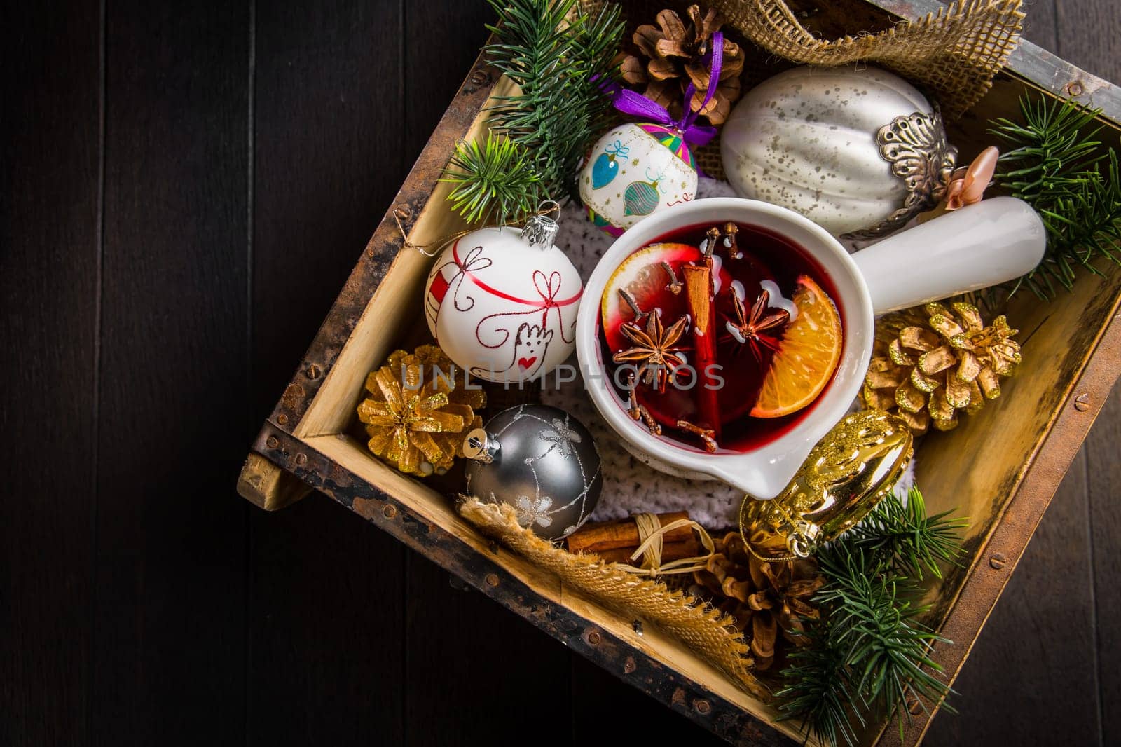Mulled wine with orange, cinnamon and anise in mug with Christmas ornaments