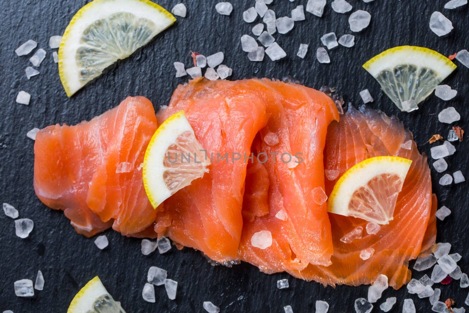 Smoked salmon with lemon and sea salt on black background. Healthy food concept.