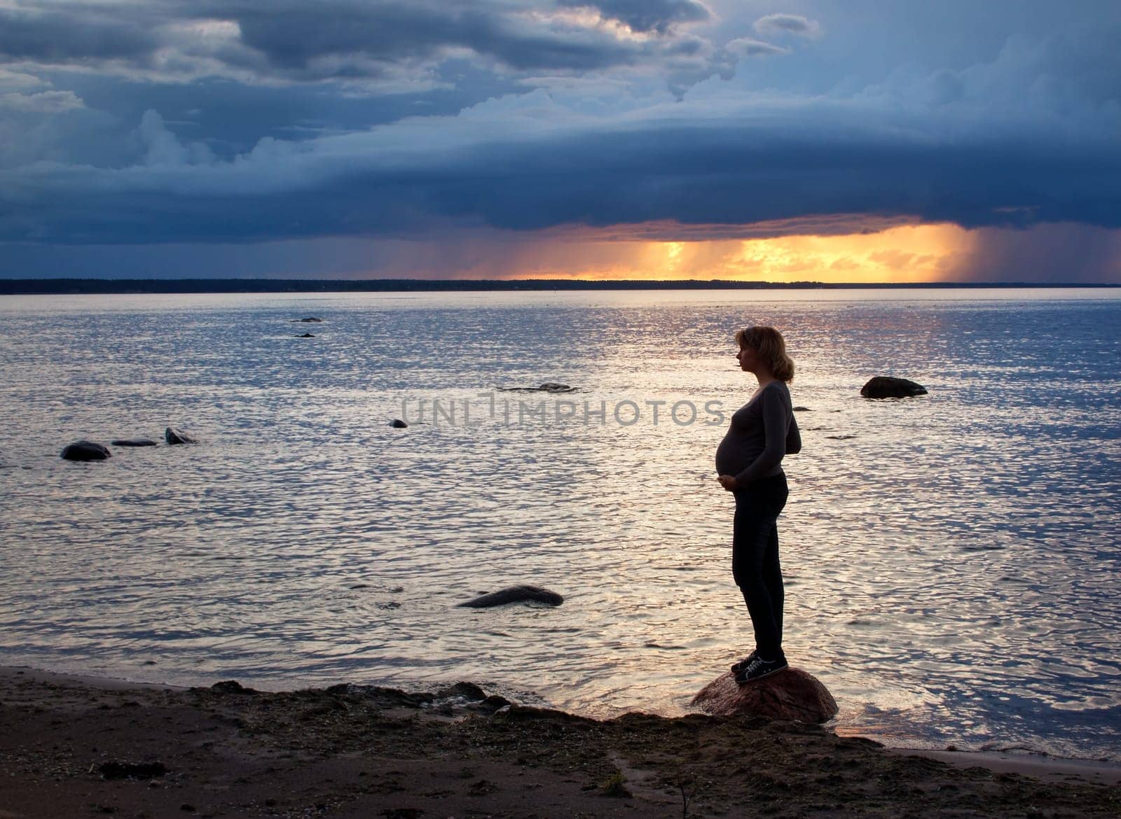Pregnant woman standing at sunset on the coast