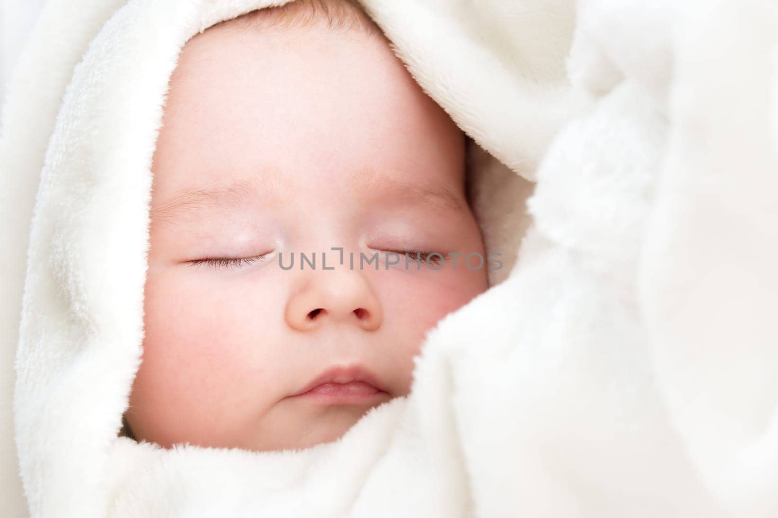 little boy sleeping on soft white blanket