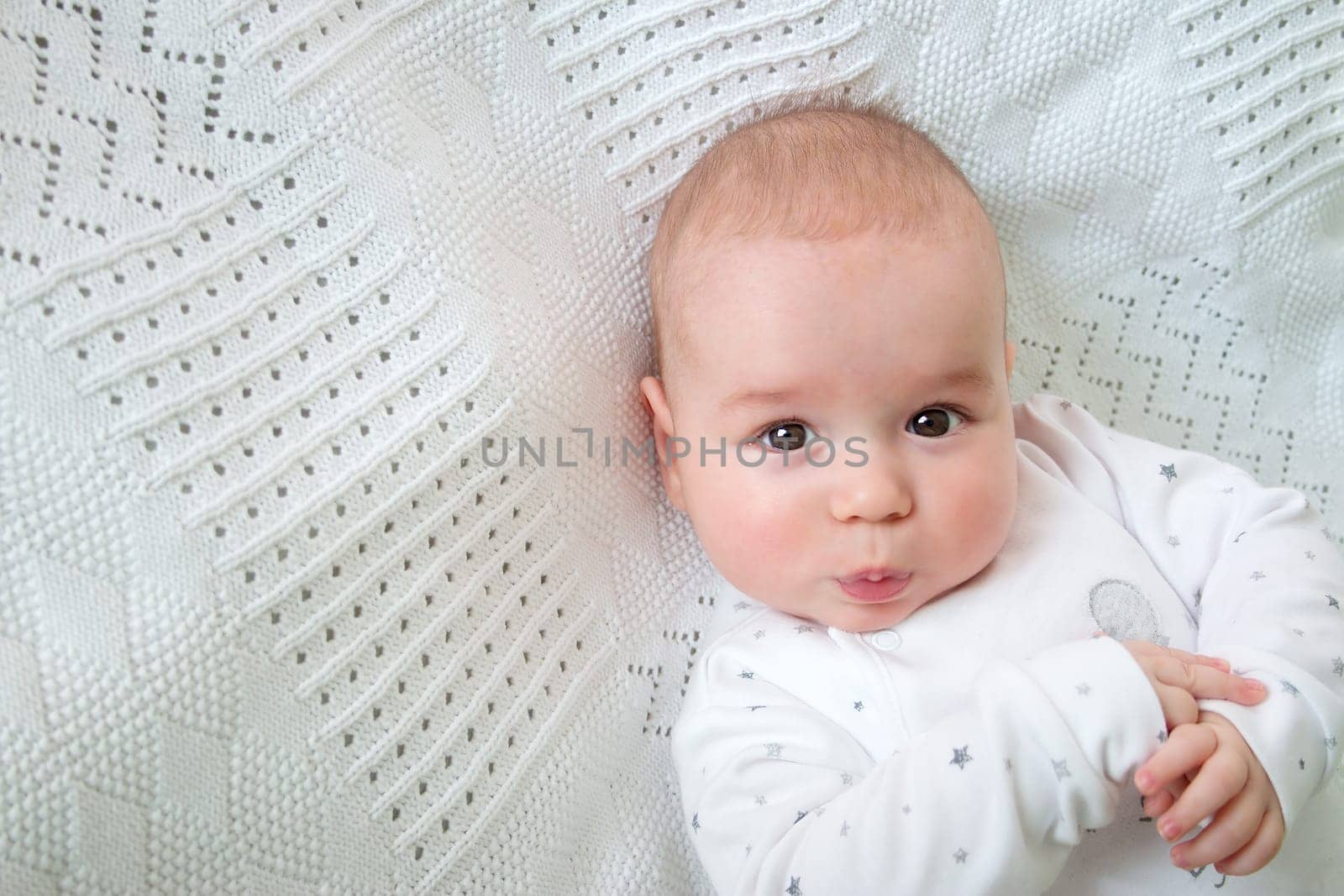 little boy lying on soft white blanket