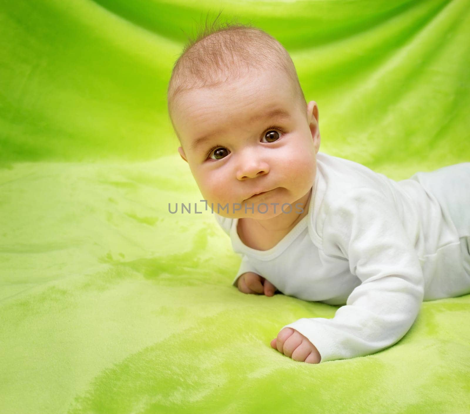 little boy lying on soft green blanket