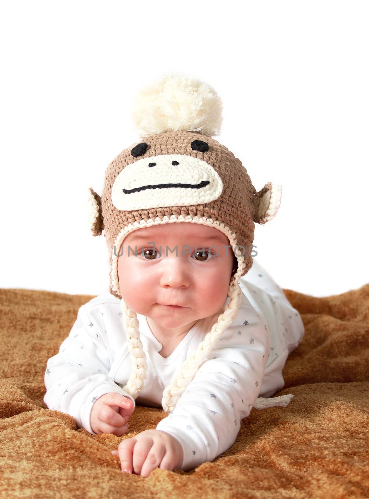 little baby in knitted montey hat on brown blanket