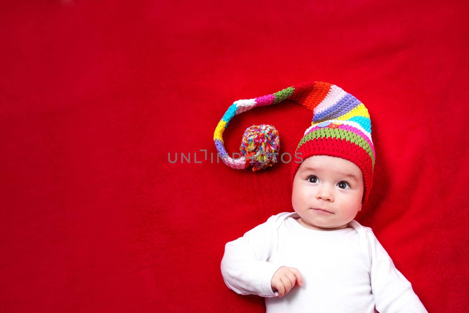 Baby in red and white hat on the bed