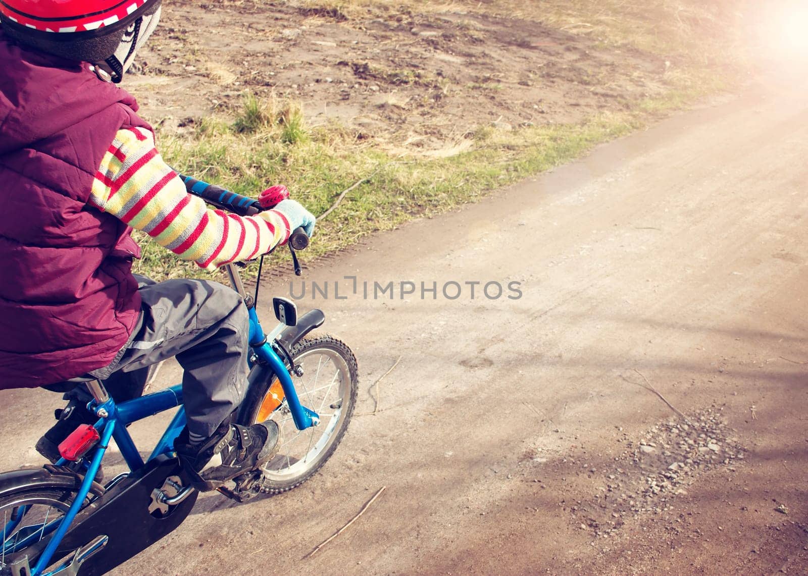 Boy on bike at gravel road in spring