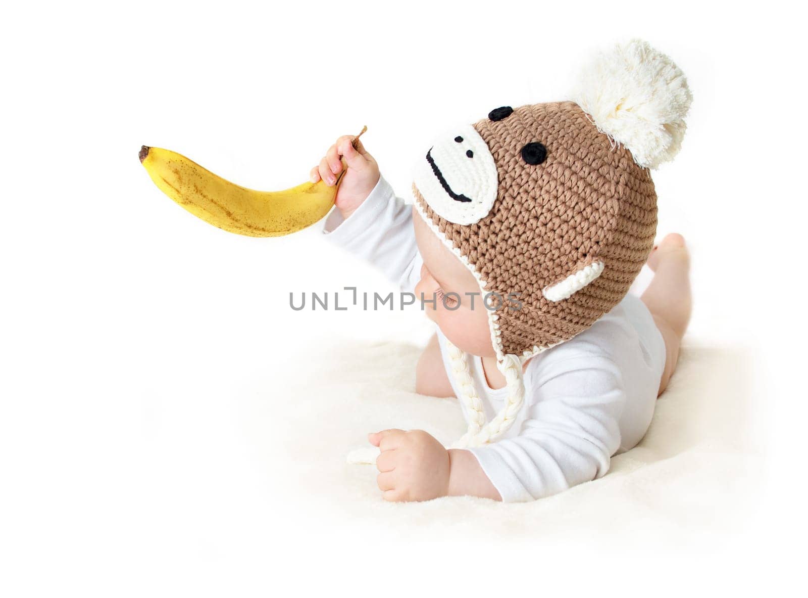 little baby in knitted montey hat on brown blanket