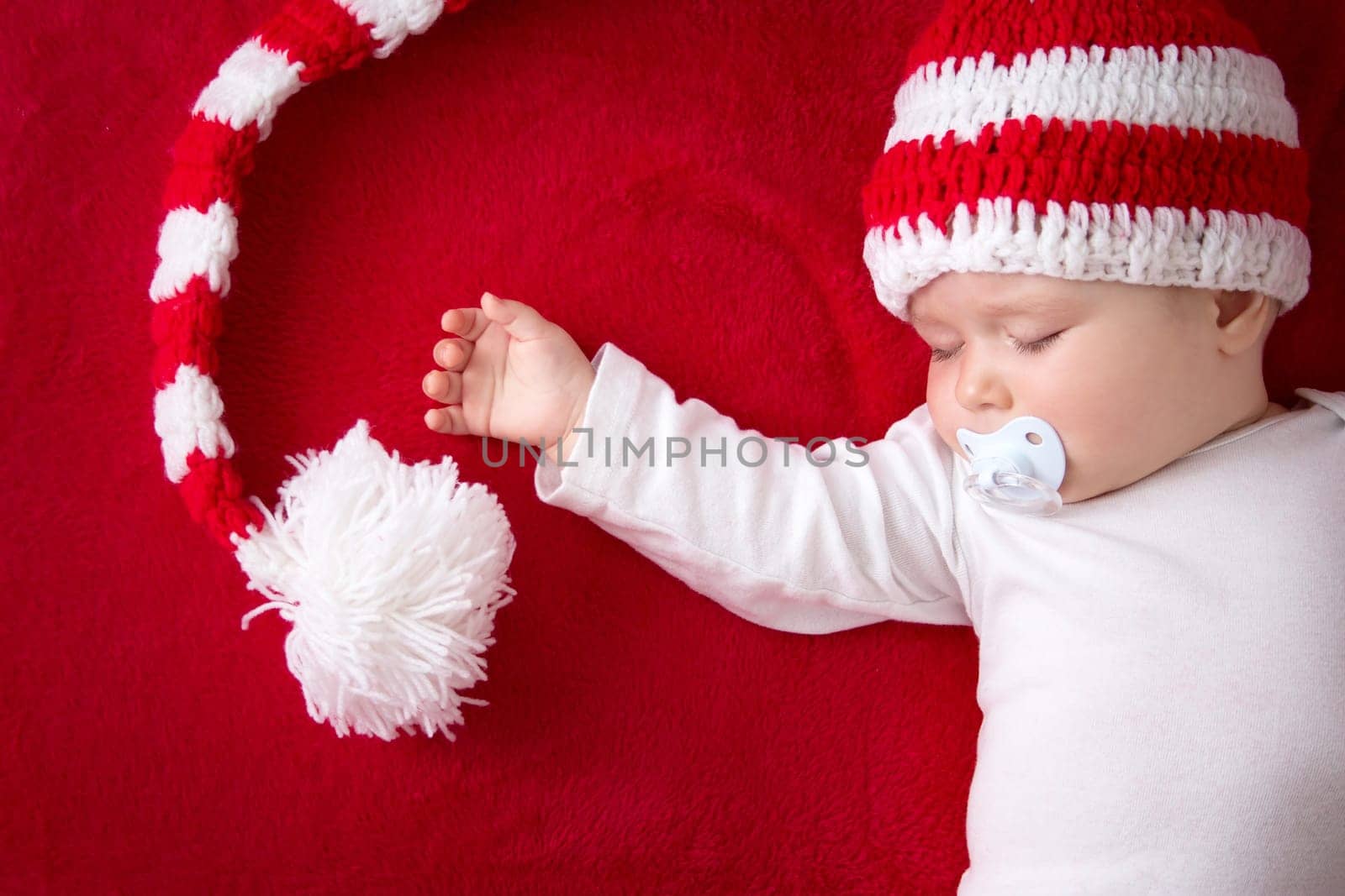 little baby in knitted red whitey hat on red blanket