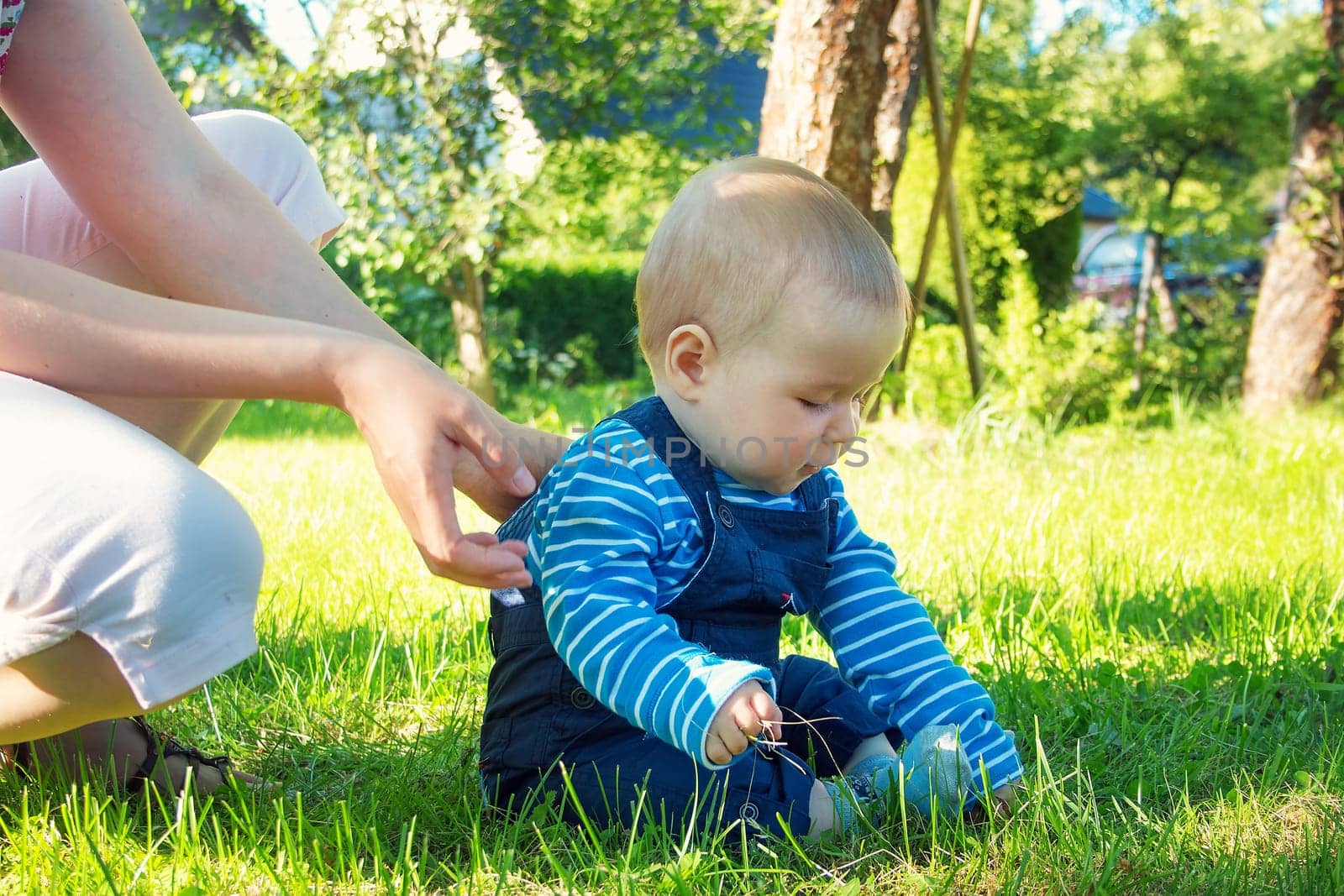 Baby boy sitiing on the grass in the garden