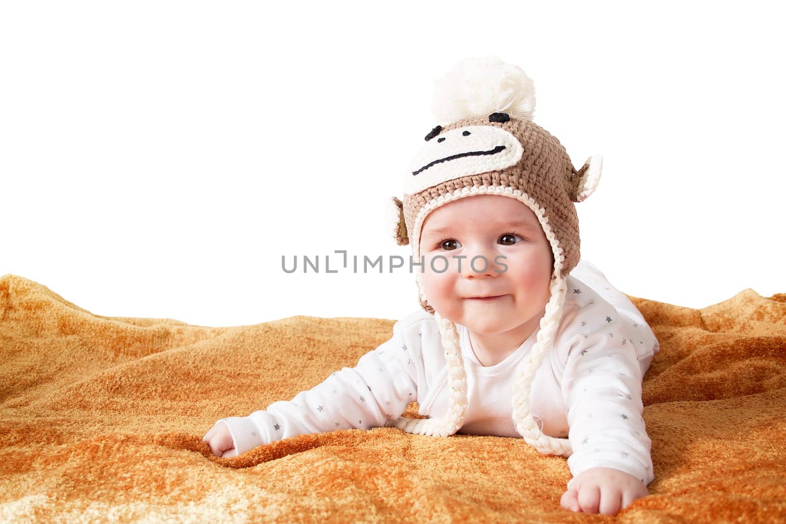 little baby in knitted montey hat on brown blanket