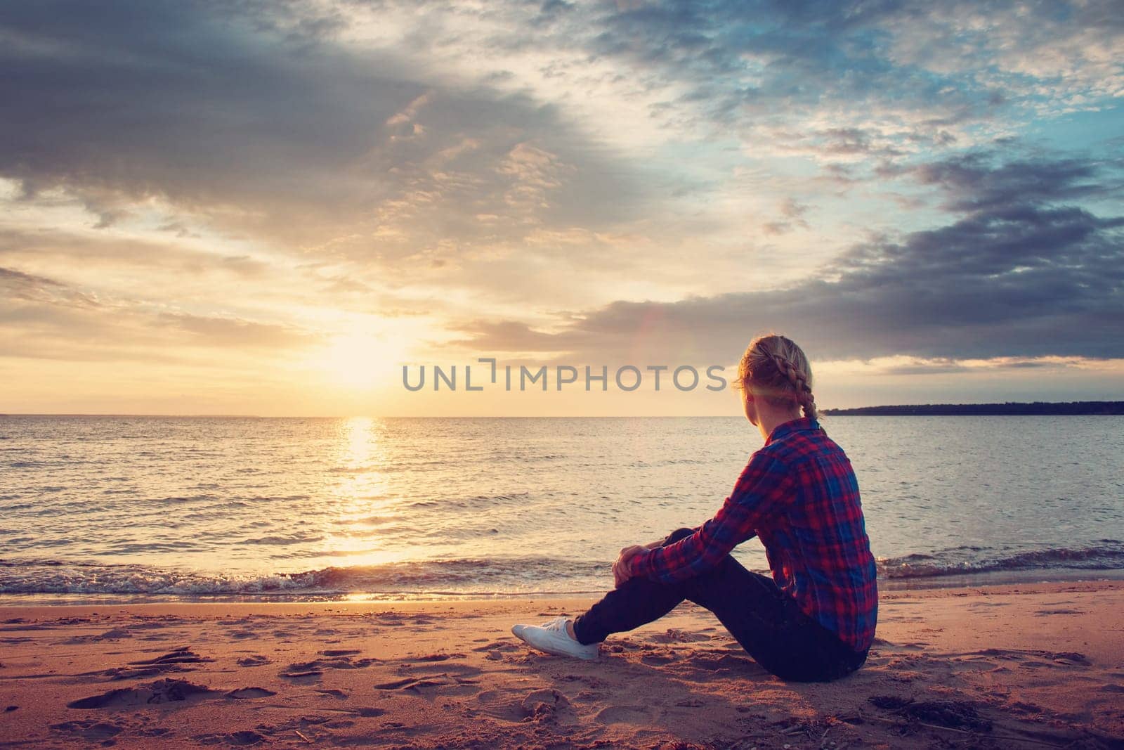 young blond woman looking at setting sun