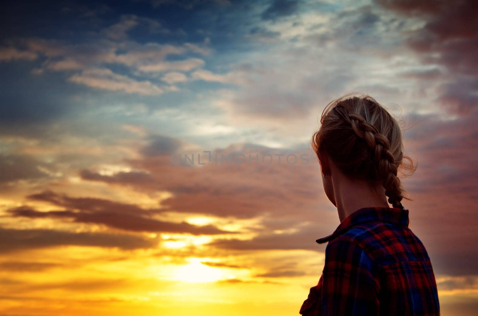 young blond woman looking at setting sun