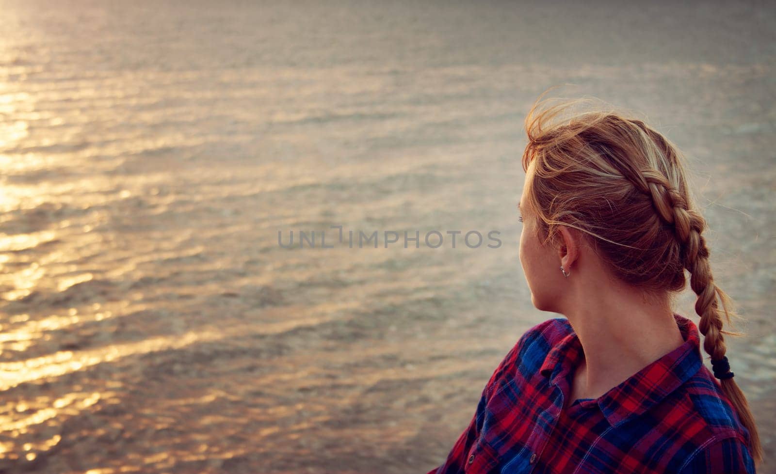 young blond woman looking at setting sun