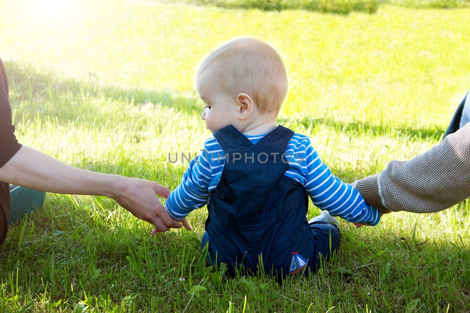 Baby with mother and father holding hands on the nature