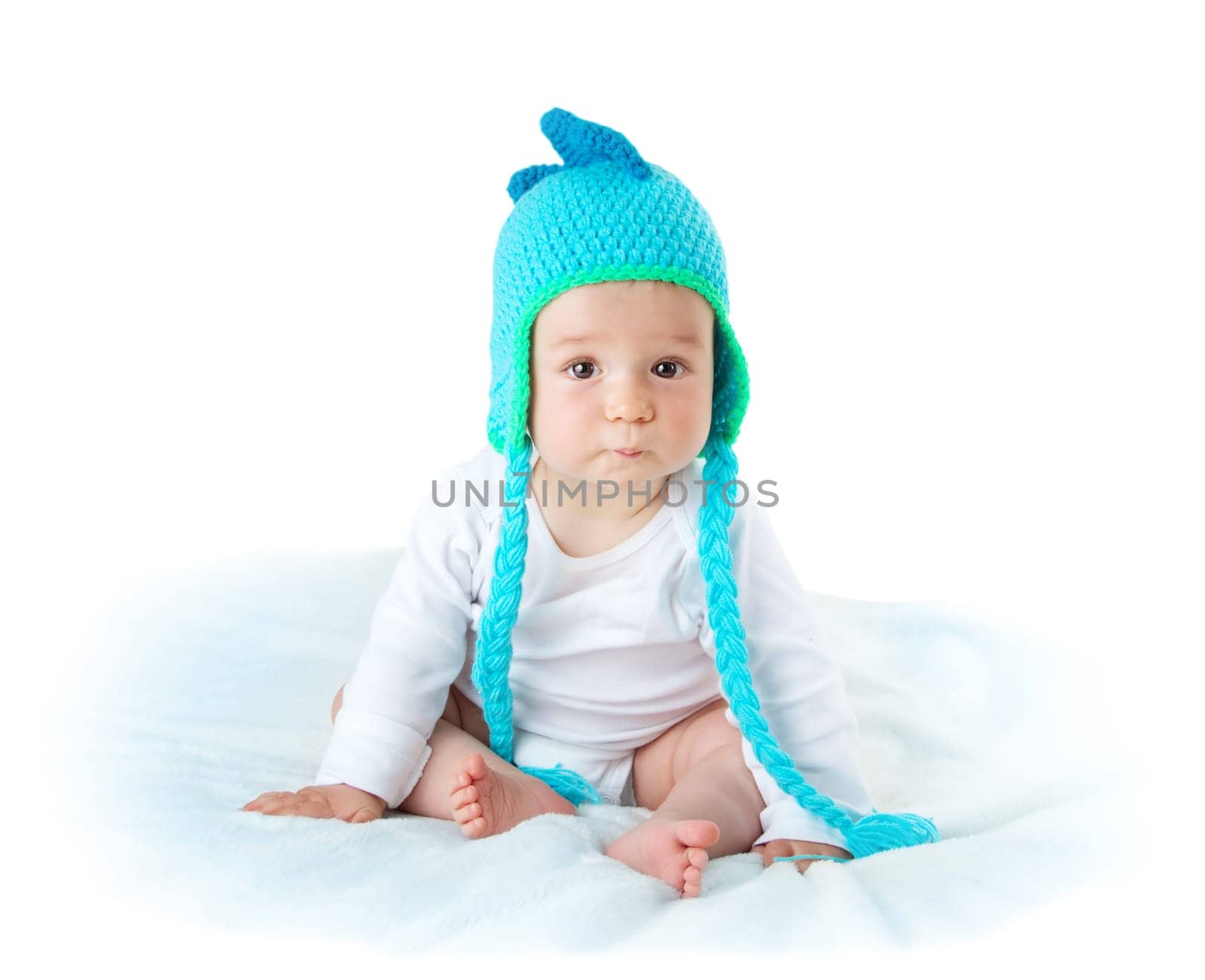 little baby in knitted dinosaur hat on soft blanket