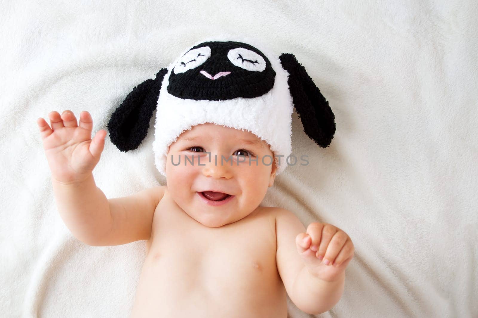 cute baby in a sheep hat lying on soft blanket
