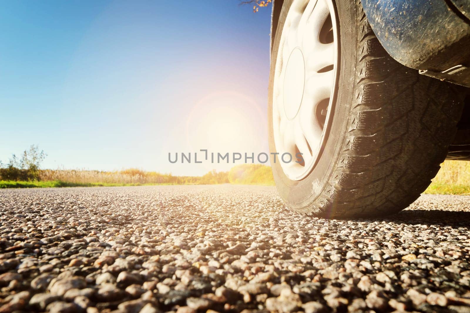 Car wheel on asphalt road in autumnal evening