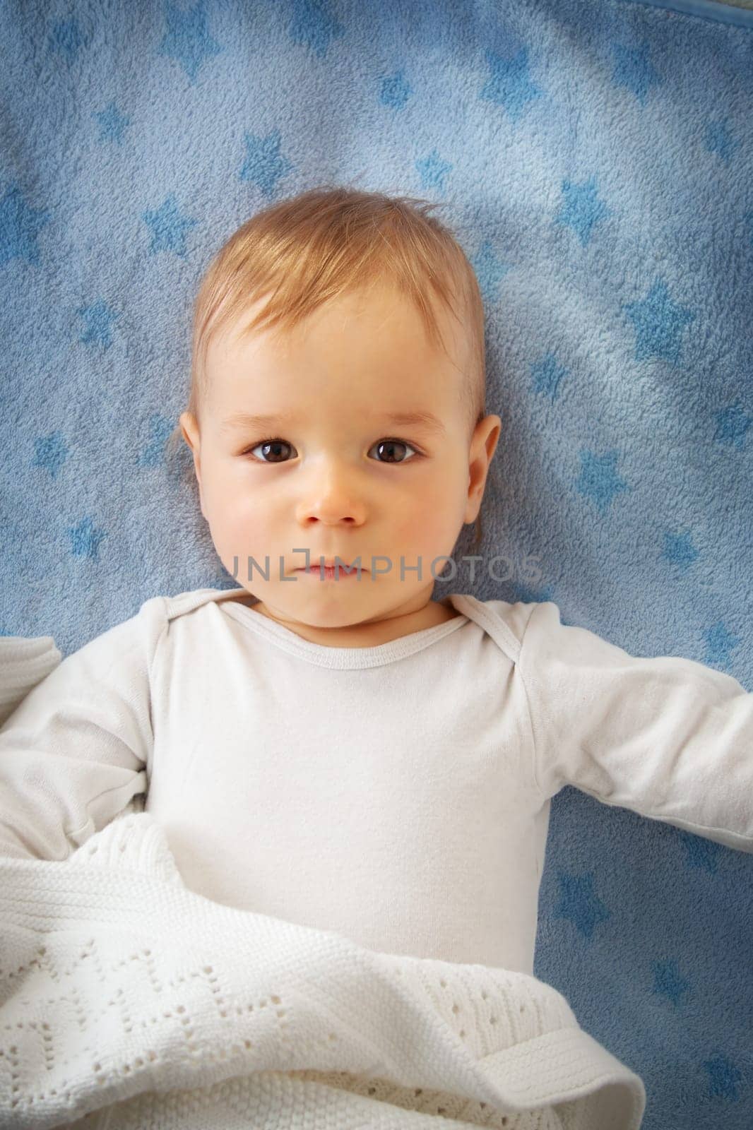 One year old baby lying on blue towel with stars
