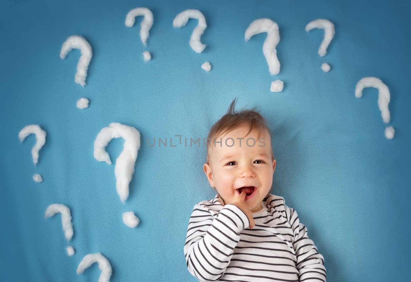 little boy lying on blue blanket with lots of question marks