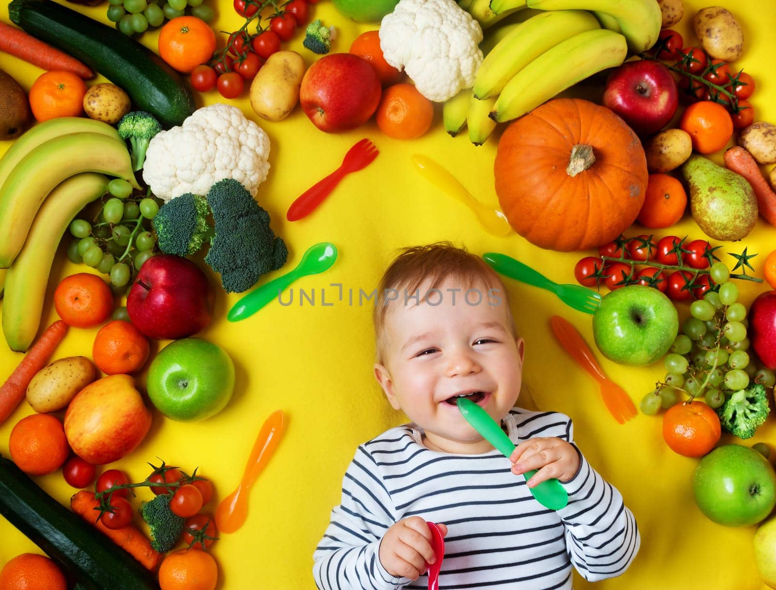 baby surrounded with fruits and vegetables on yellow blanket, healthy child nutrition