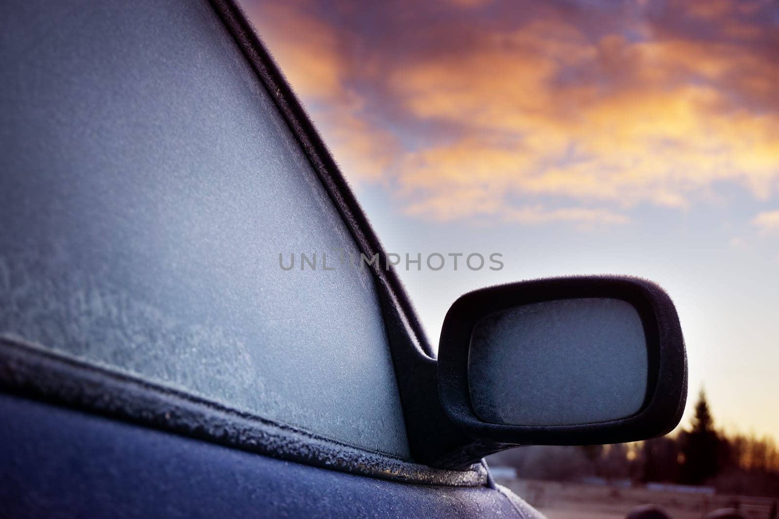 Car window and side mirror covered with ice in early morning