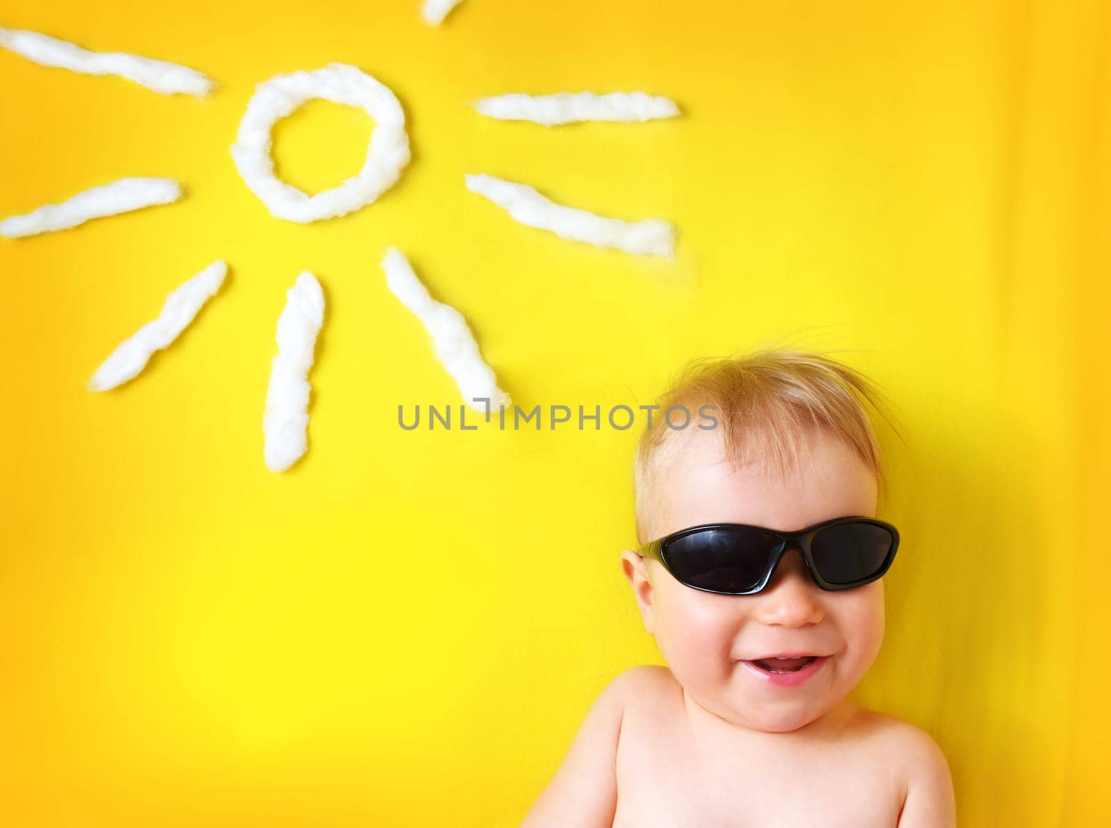 little boy with sunglasses and sun shape on yellow blanket