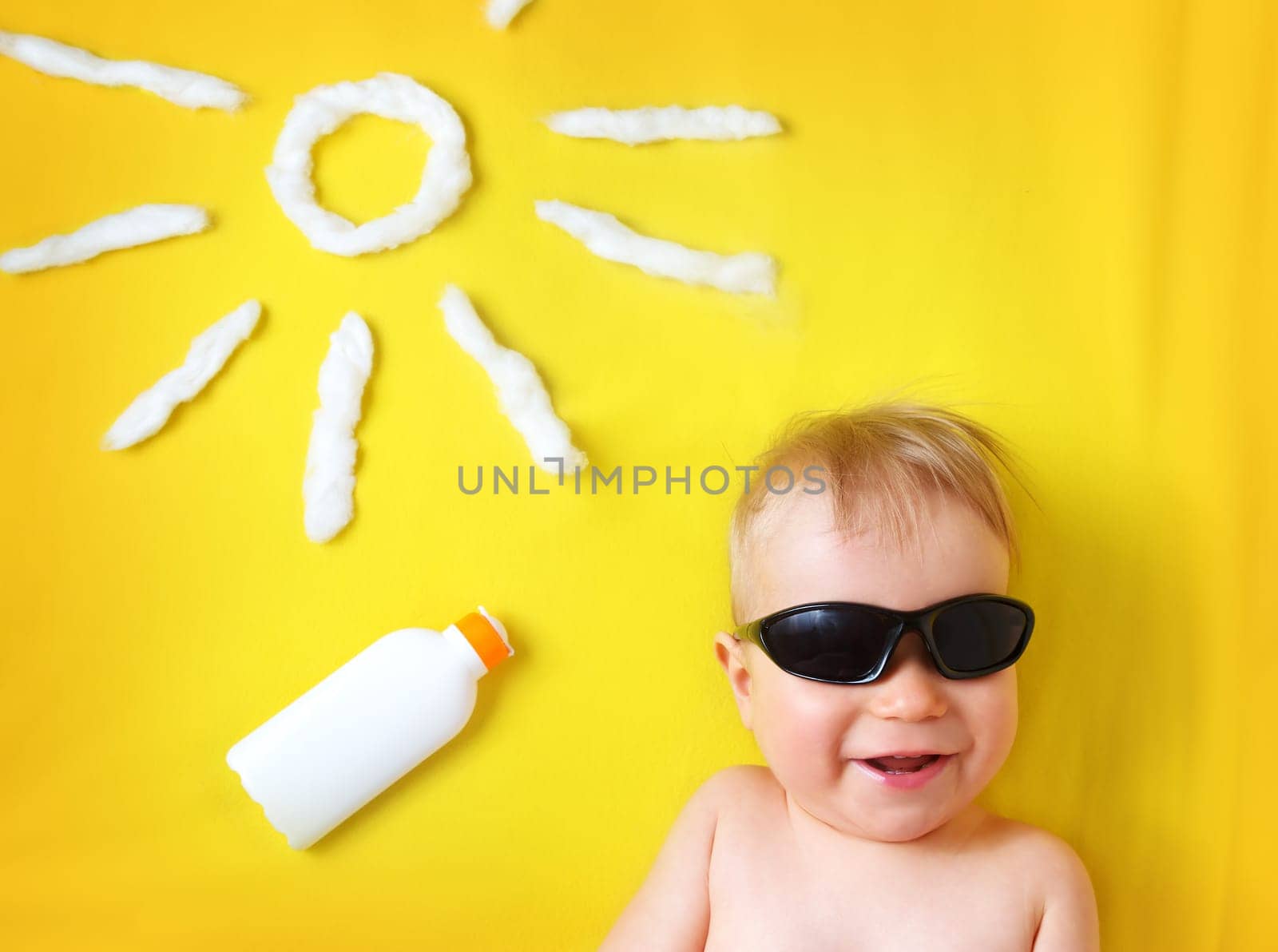 little boy with sunglasses and sun shape on yellow blanket