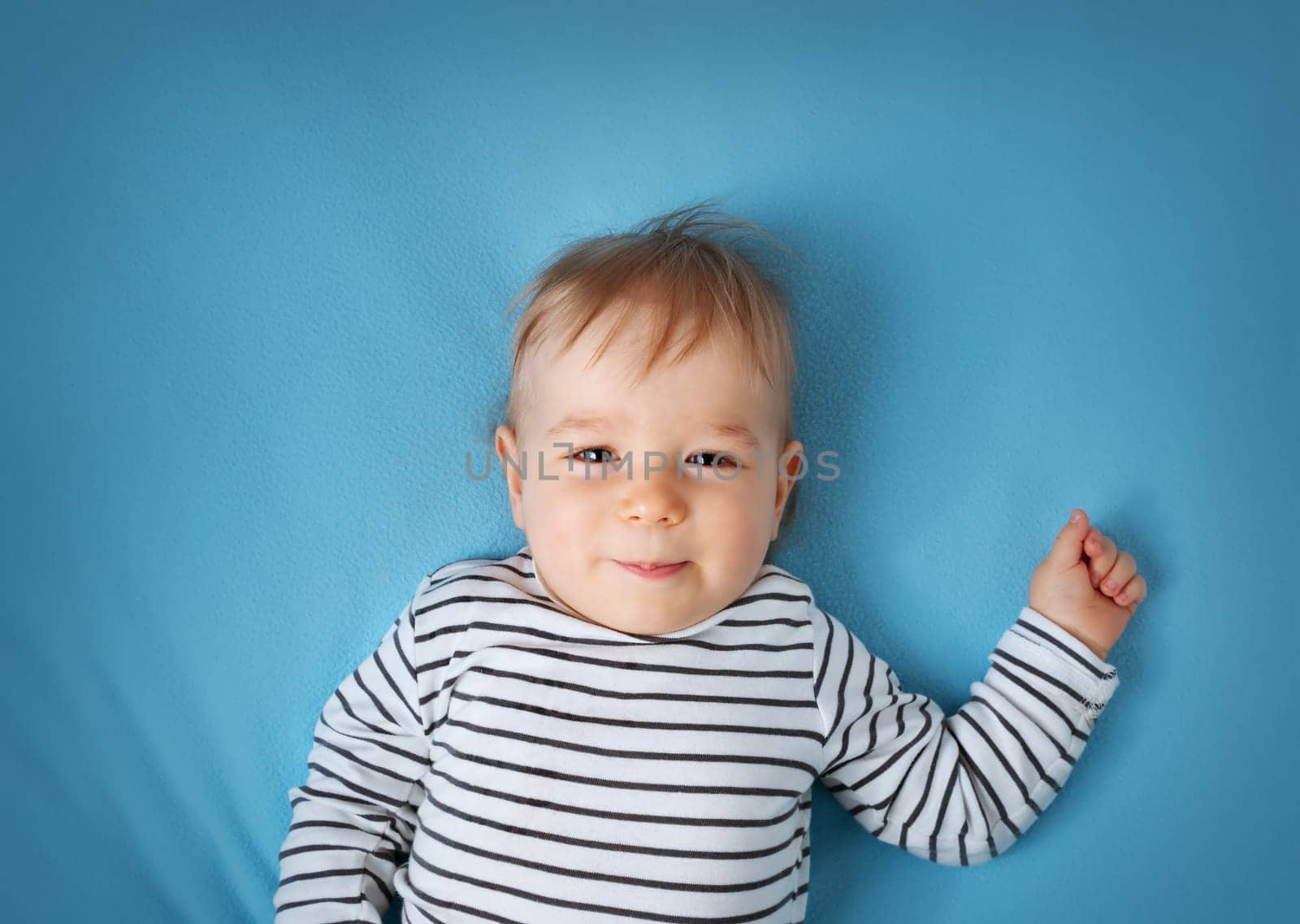 happy little boy on blue blanket background