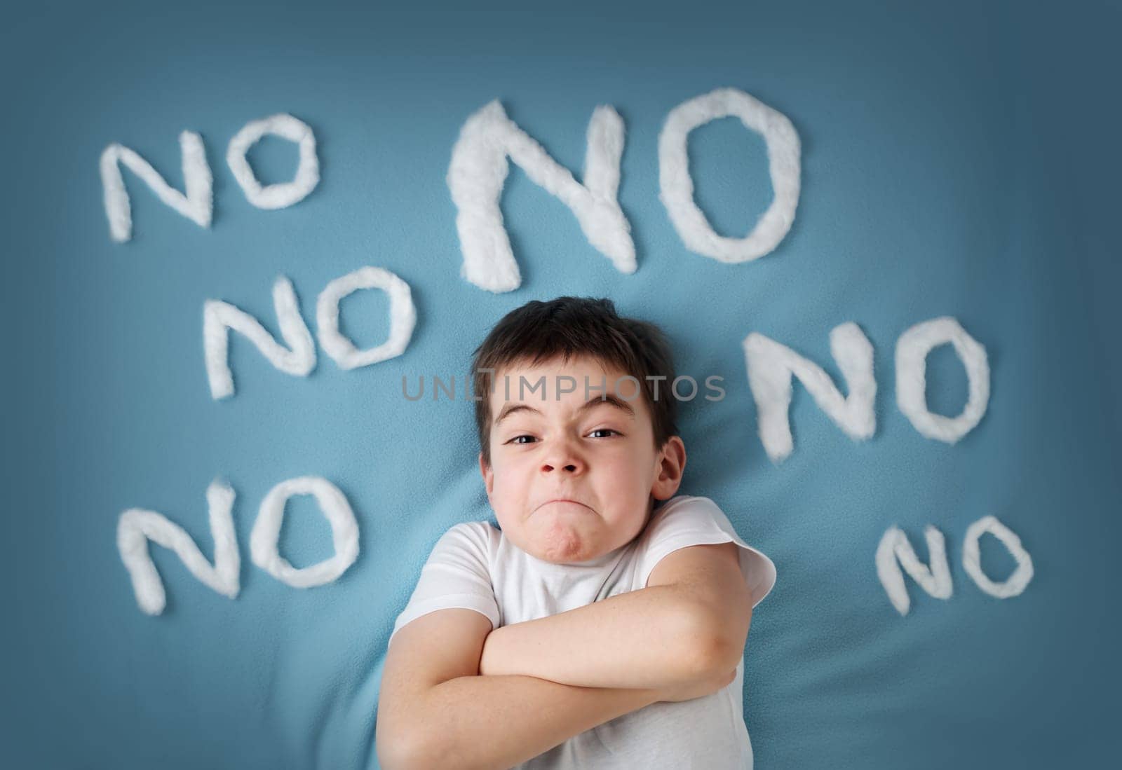 bad boy on blue blanket background. Angry child with no words around