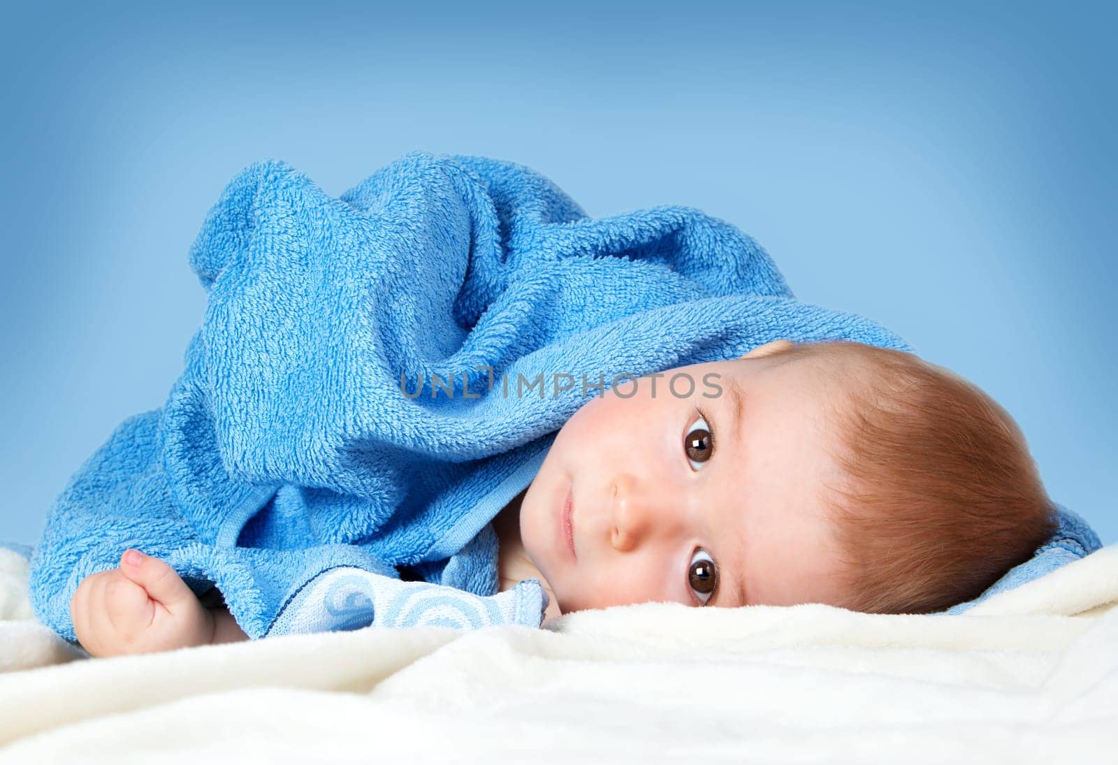 Cute eight month old baby wrapped in a towel. Baby hygiene. Adorable little boy