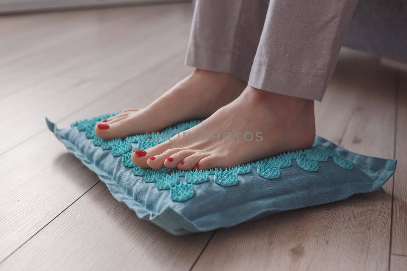 Female feet standing on acupressure mat. Self acupuncture massage. Woman having alternative medicine treatment.