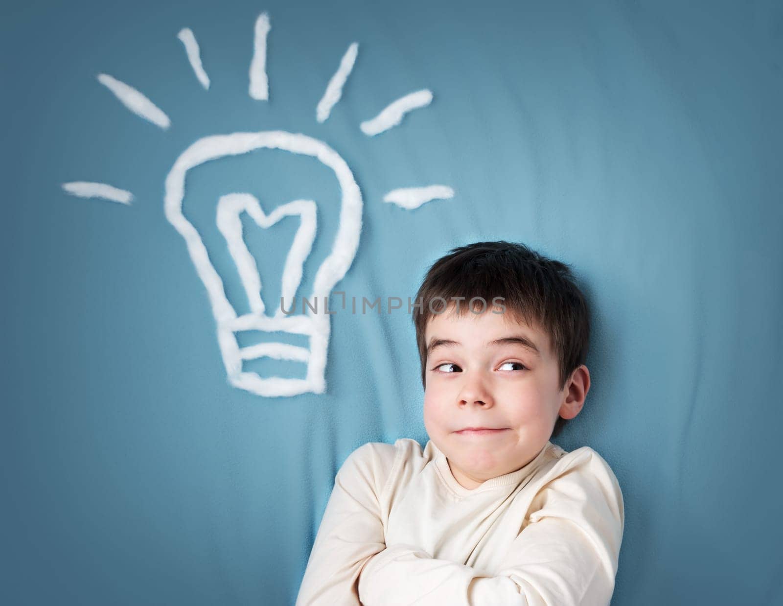 seven years old boy with a bulb on blue background. Child with an idea