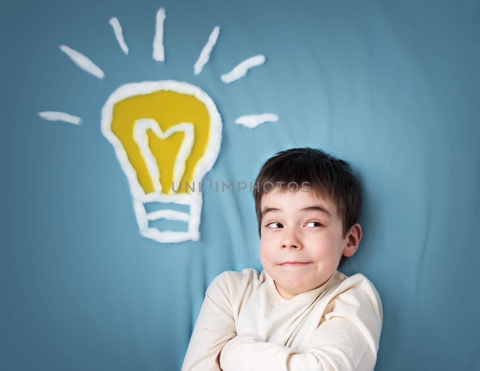 seven years old boy with a bulb on blue background. Child with an idea
