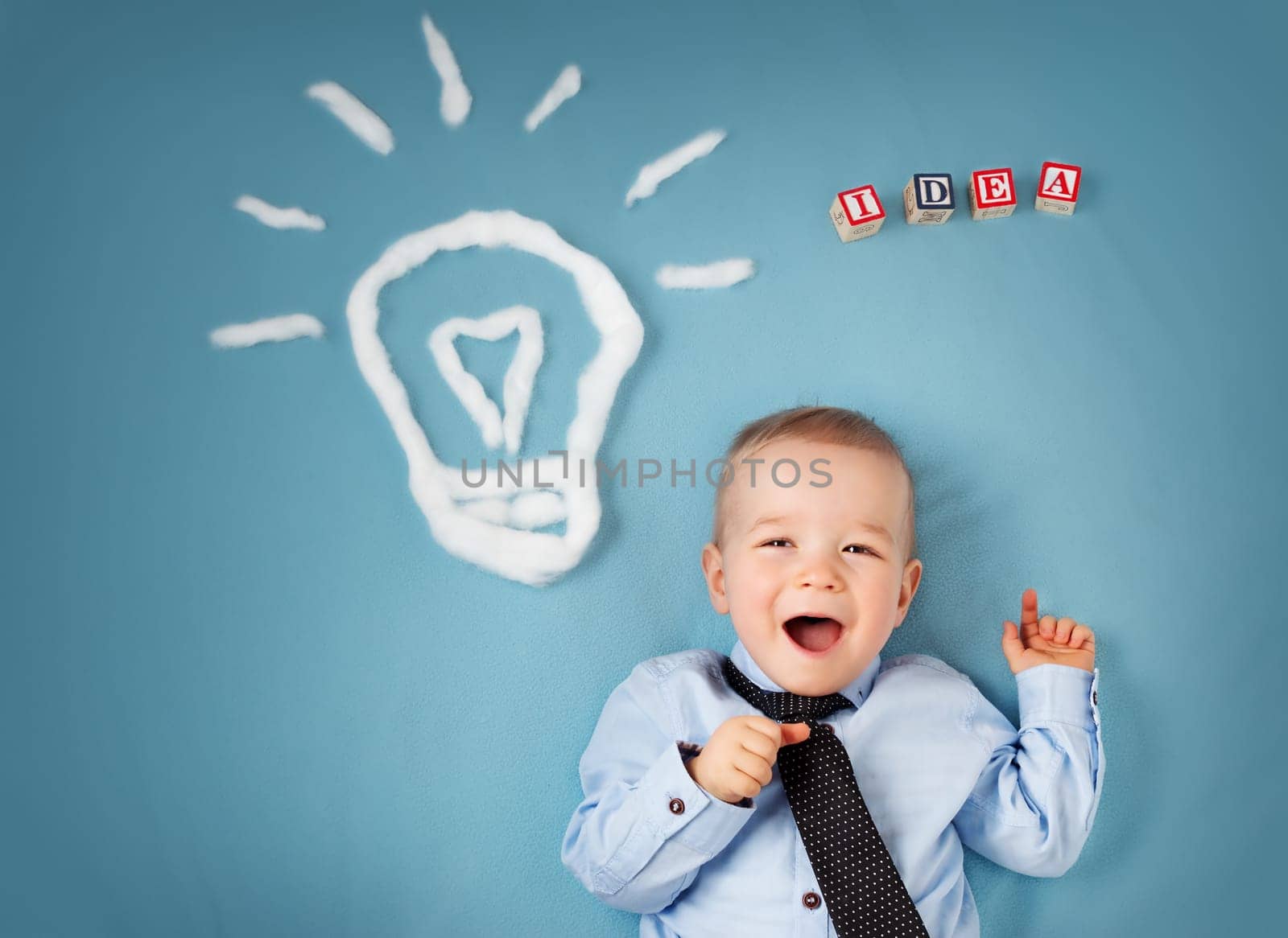One year old boy with a bulb on blue background. Child with an idea