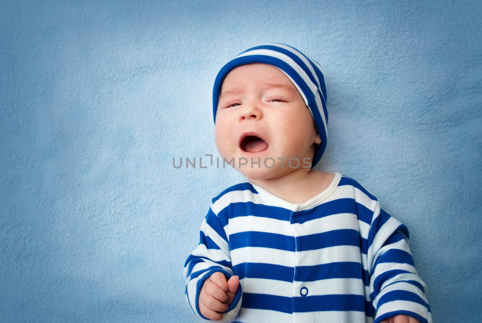 sleepy little boy crying on soft blue blanket