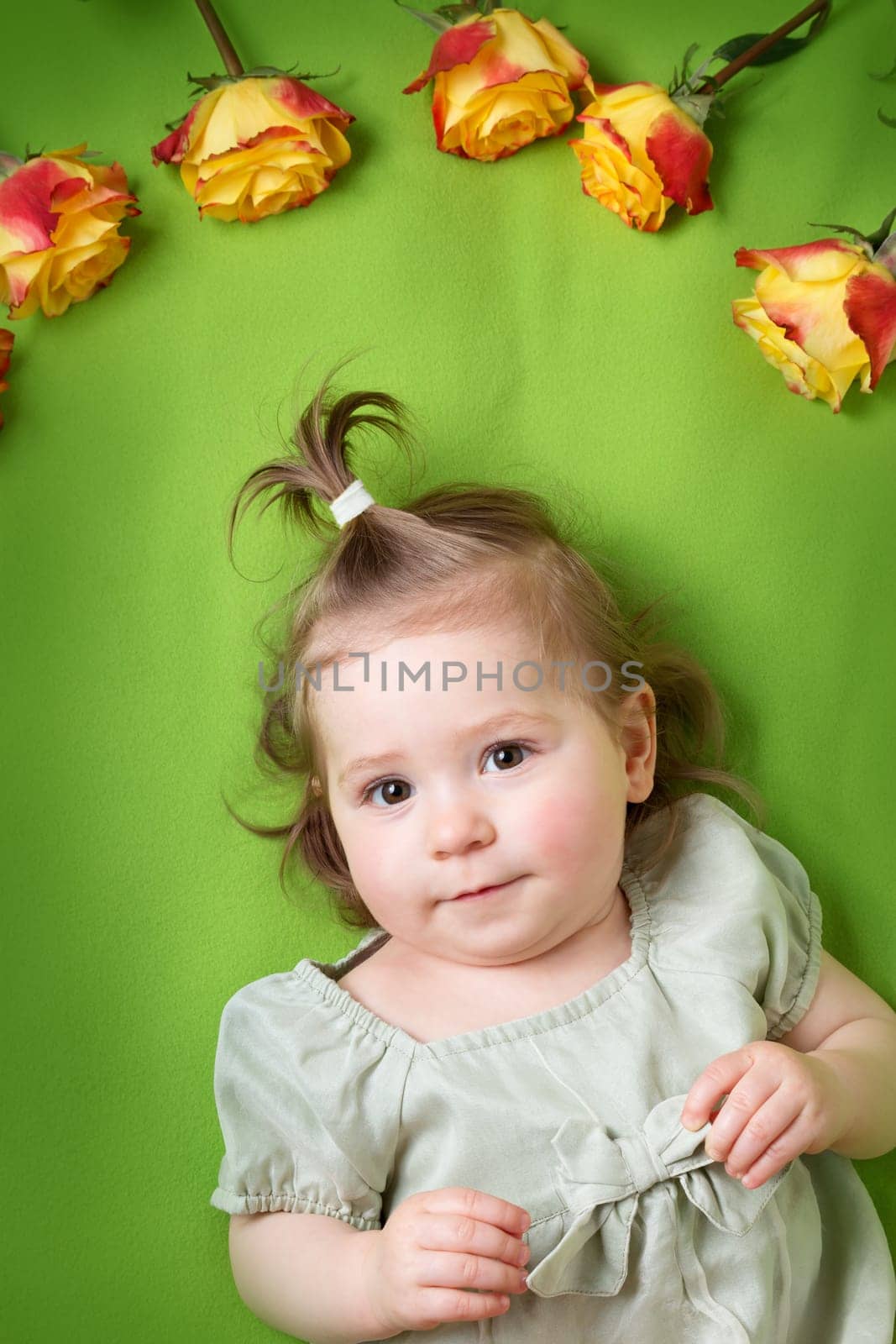 pretty one year old babygirl lying on green blanket with yellow roses