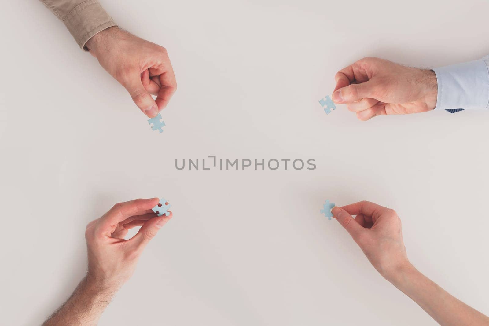 Hands with puzzle items isolated on white background. Team problem solving. Top view. Mutual assistance of business and individuals