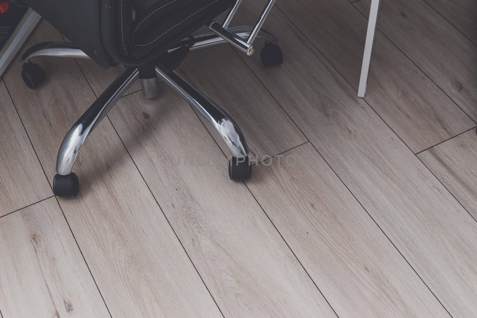 Close up of office chair wheels on wooden floor